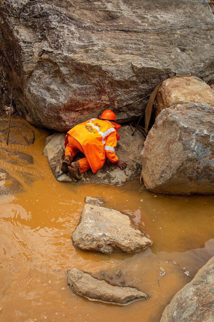 Machines (left) are helping move soil and find people. A volunteer (right) searches for bodies along the river