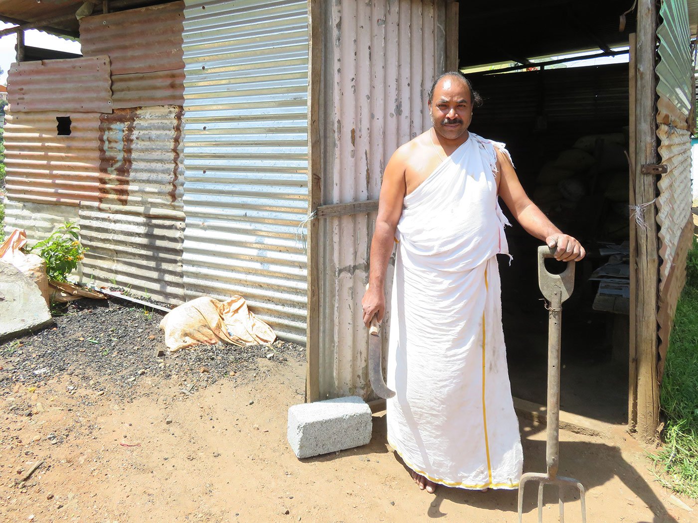 Kollel Rangan is also a Kota priest and must wear the traditional Kota dress even while working at his smithy. He is holding a large size sickle and rake once used to clear the hills for agriculture.