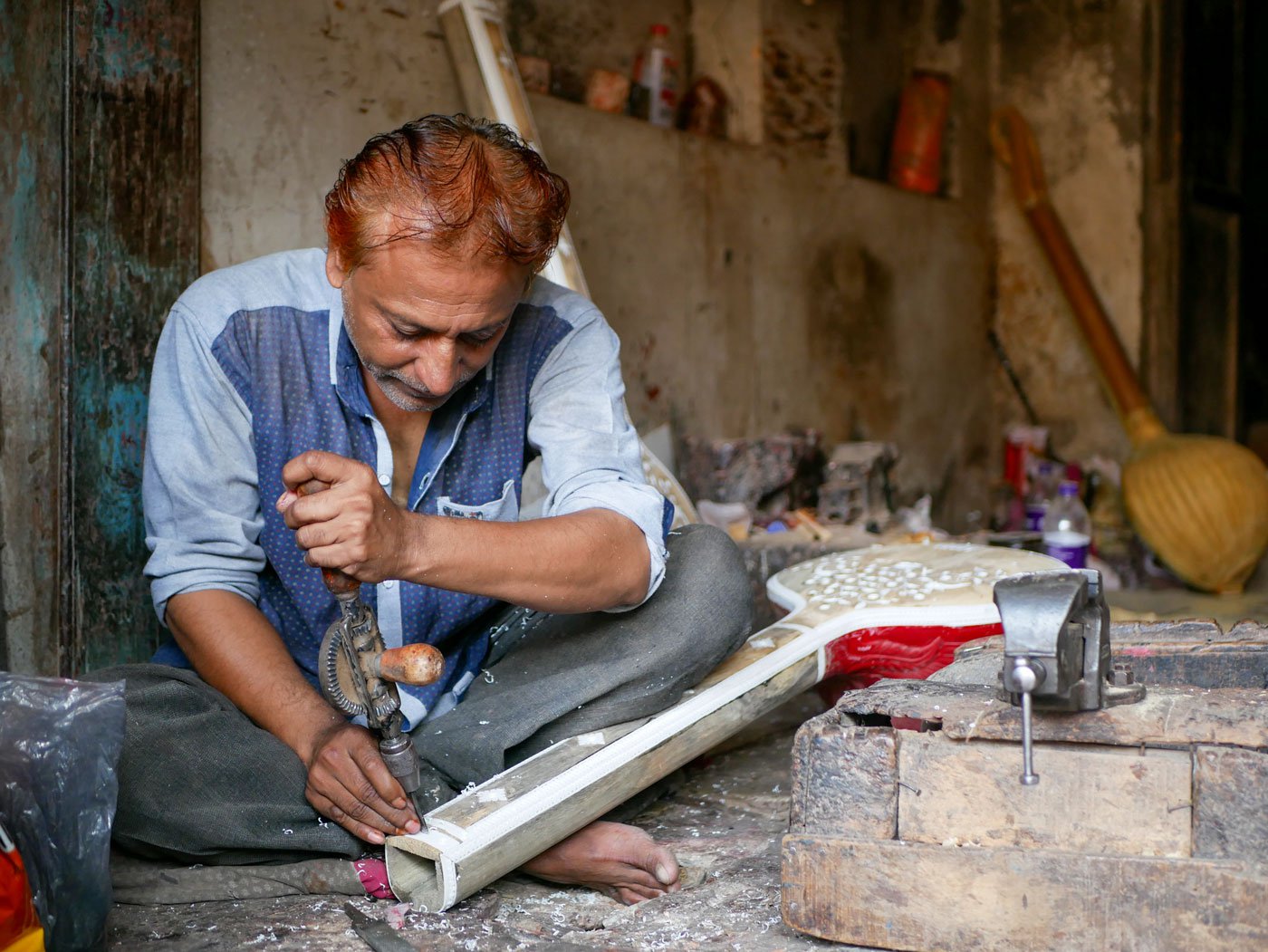Left: Irfan Sitarmaker carves patterns and roses on the sitar's handle using a hand drill.