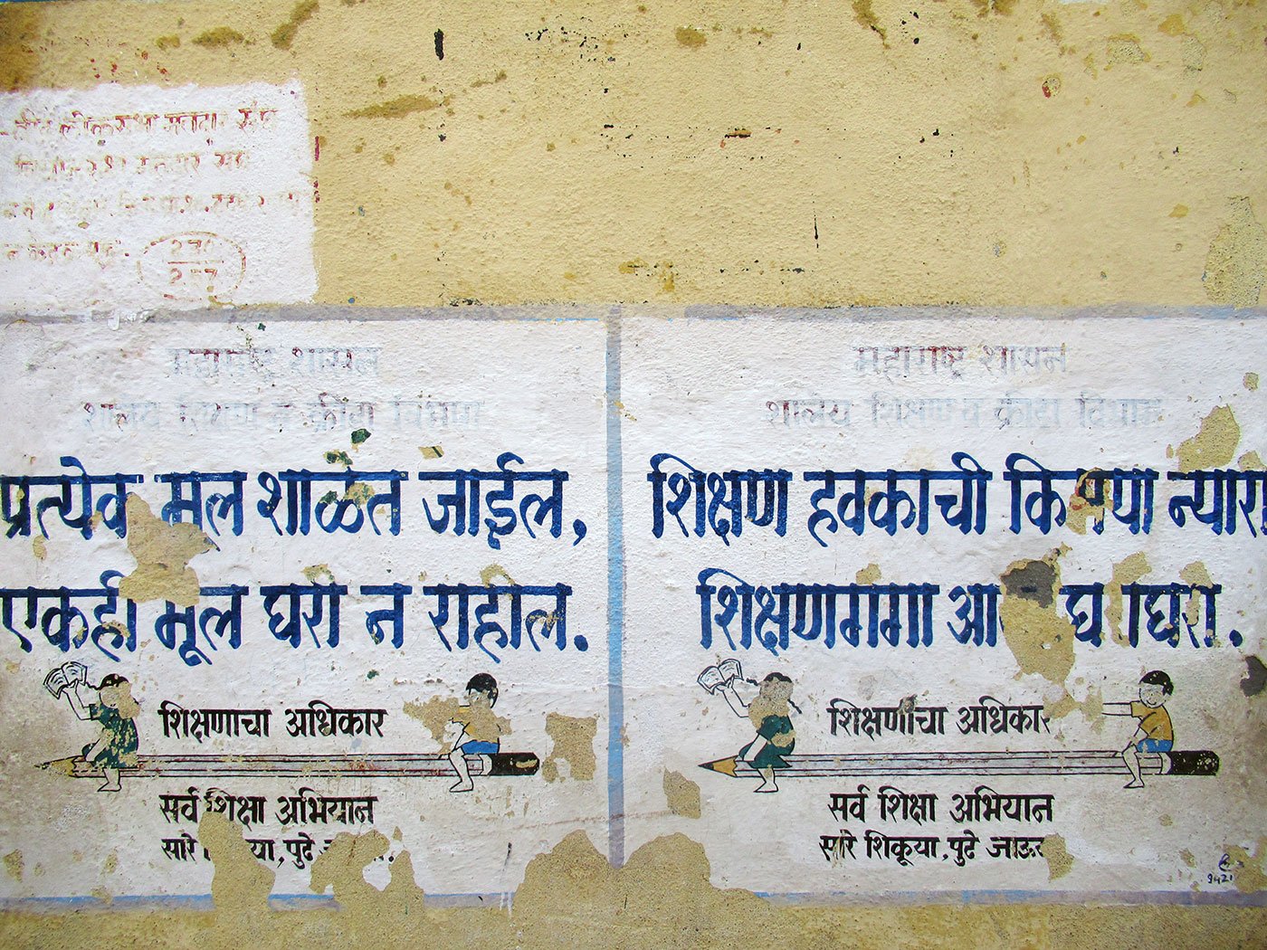 Torn posters on a yellow wall school wall in Marathi at Hatkarwadi village in Beed district of Maharashtra. It says, “Every kid will go to school, nobody will be at home”.