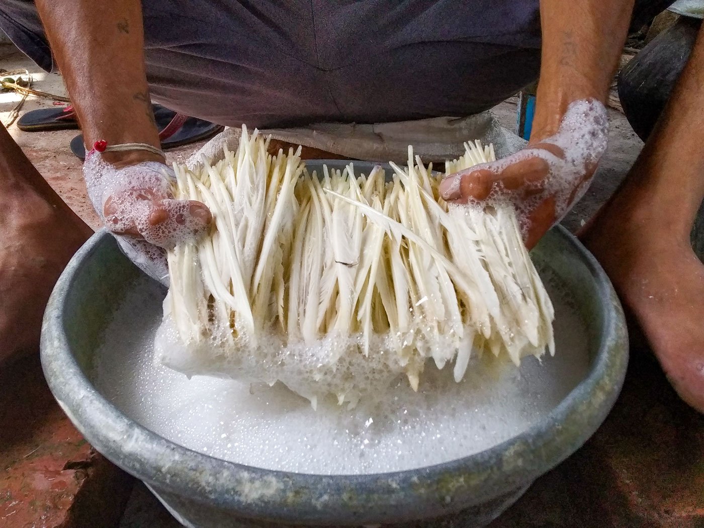 Ranjit scrubs the feathers batch by batch in warm soapy water. 'The feathers on a shuttle have to be spotless white,' he says. On the terrace, the craftsman lays out a black square tarpaulin sheet and spreads the washed feathers evenly. Once they are dry, they will be ready to be crafted into shuttlecocks.