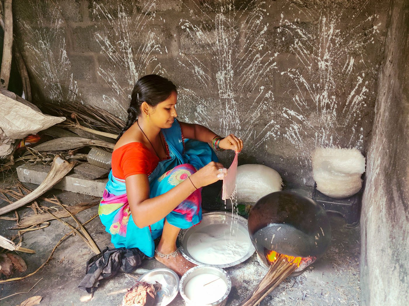 Veteran sweet maker, Vijaya has been making reku since 2019 and she says she always has to give it her full concentration. When she dips the cloth in the rice batter and lays it on the pot, a film forms on the inverted pot (right)