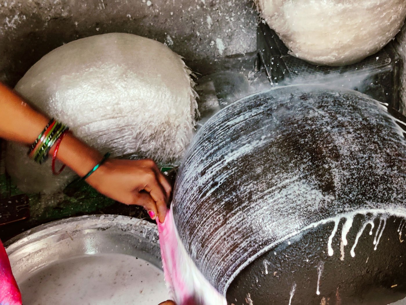 Veteran sweet maker, Vijaya has been making reku since 2019 and she says she always has to give it her full concentration. When she dips the cloth in the rice batter and lays it on the pot, a film forms on the inverted pot (right)