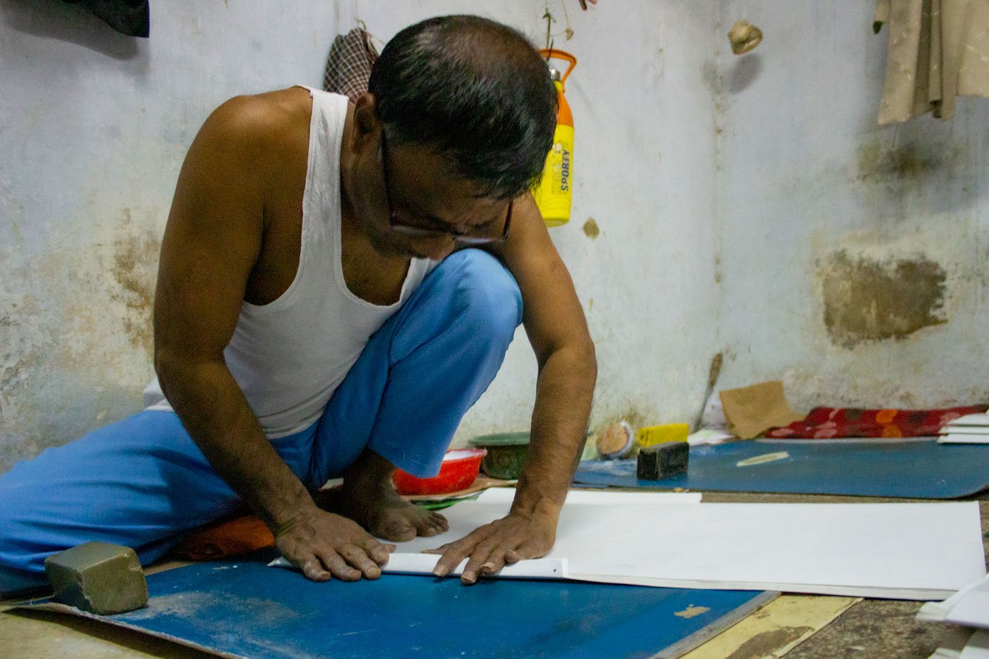 Workers begin by folding the envelope sheets to give them shape. Each flap is identified by its distinctive name – mathu (top flap), pendi (bottom flap), dhapa (right flap, where the glue will be applied), khola (let flap). Bhikbhai Rawal of Taj Envelopes is folding pendi of a large envelope to hold an x-ray