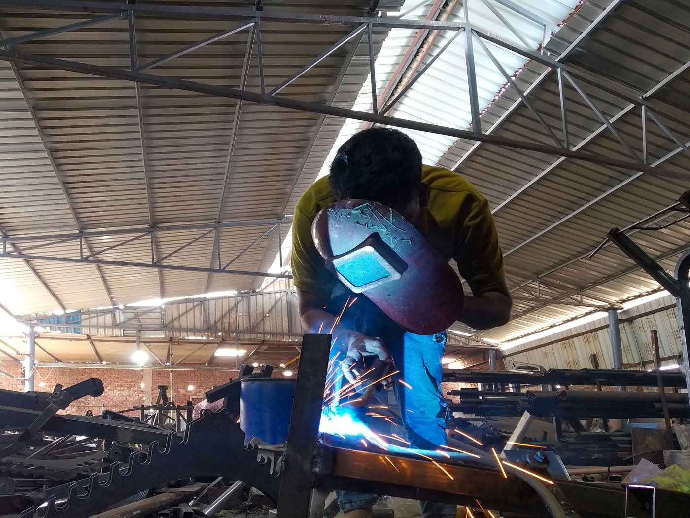 Left: Ibad Salmani uses a hand shield while strengthening the joints of gym equipment parts with a Metal Inert Gas (MIG) welder.