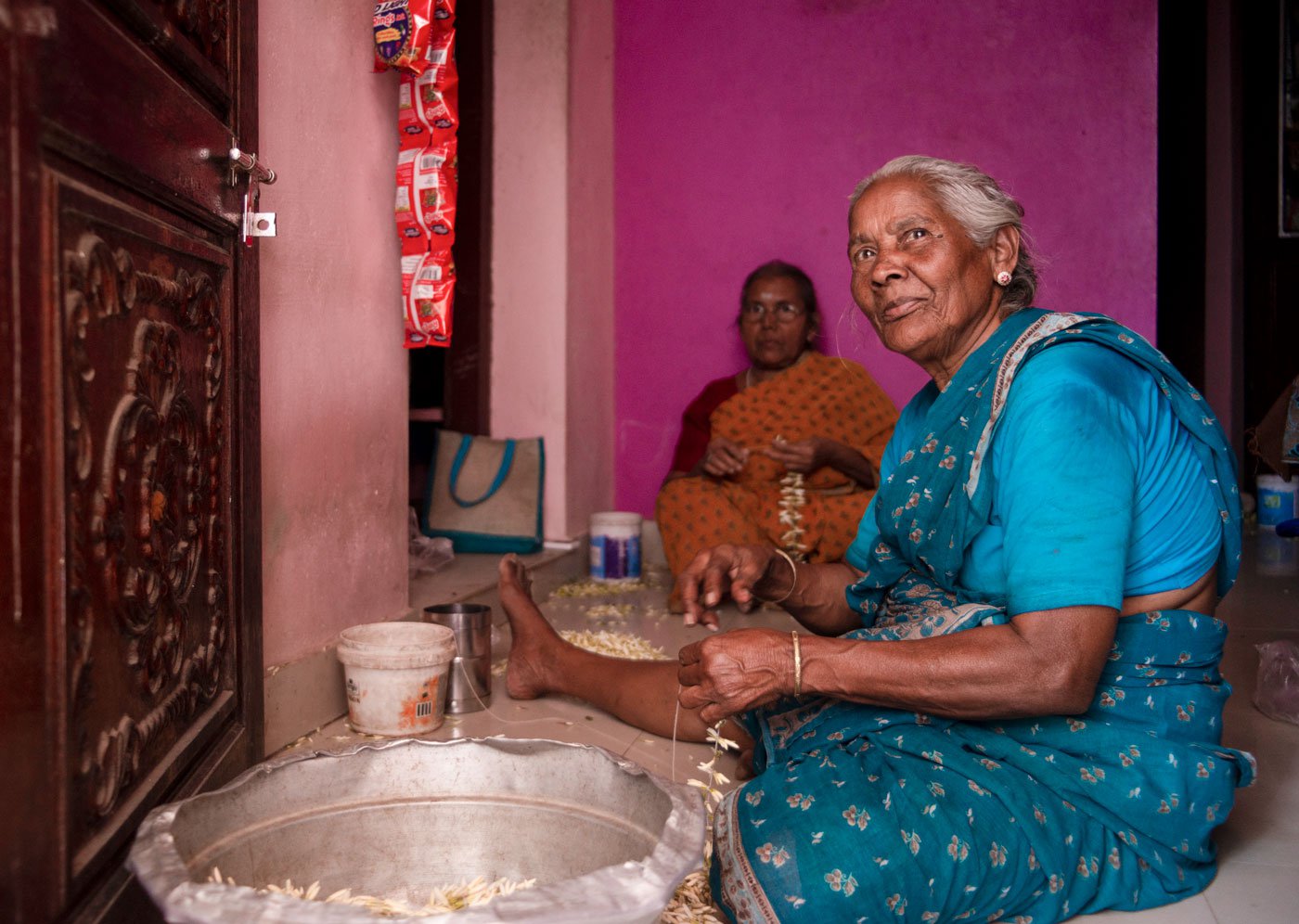Seated in her house (left) behind Thovalai market, expert stringer Meena threads (right) jasmine buds of the jathi malli variety. Now 80, she has been doing this job for decades and earns a paltry sum for her skills