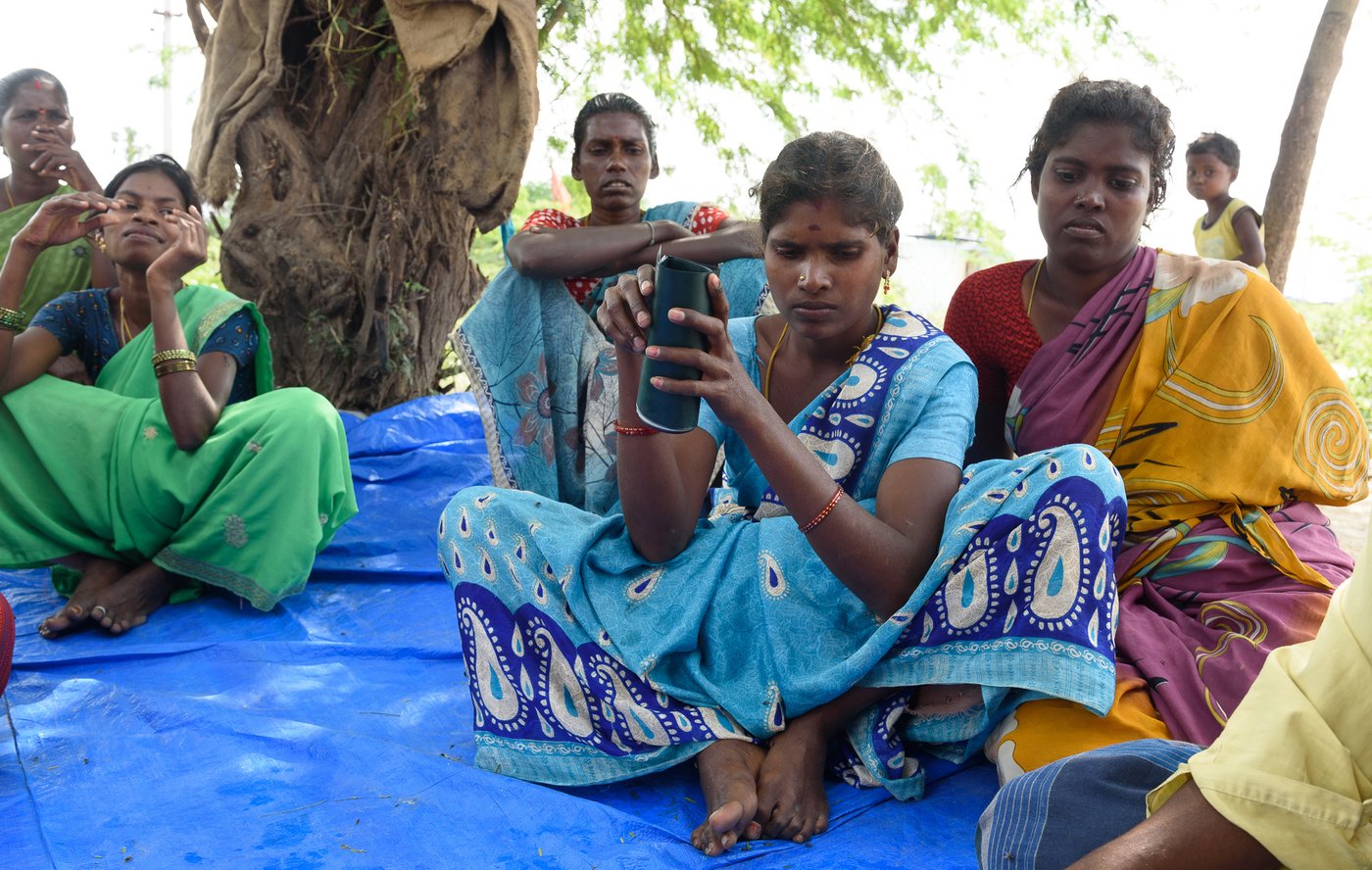 Left: The women of Bangalamedu, an Irular colony in Cherukkanur panchayat, discuss MGNREGA wages. Right: S Sumathi with her job card. The attendance and wage details on most of the job cards in this hamlet don't tally with the workers’ estimates