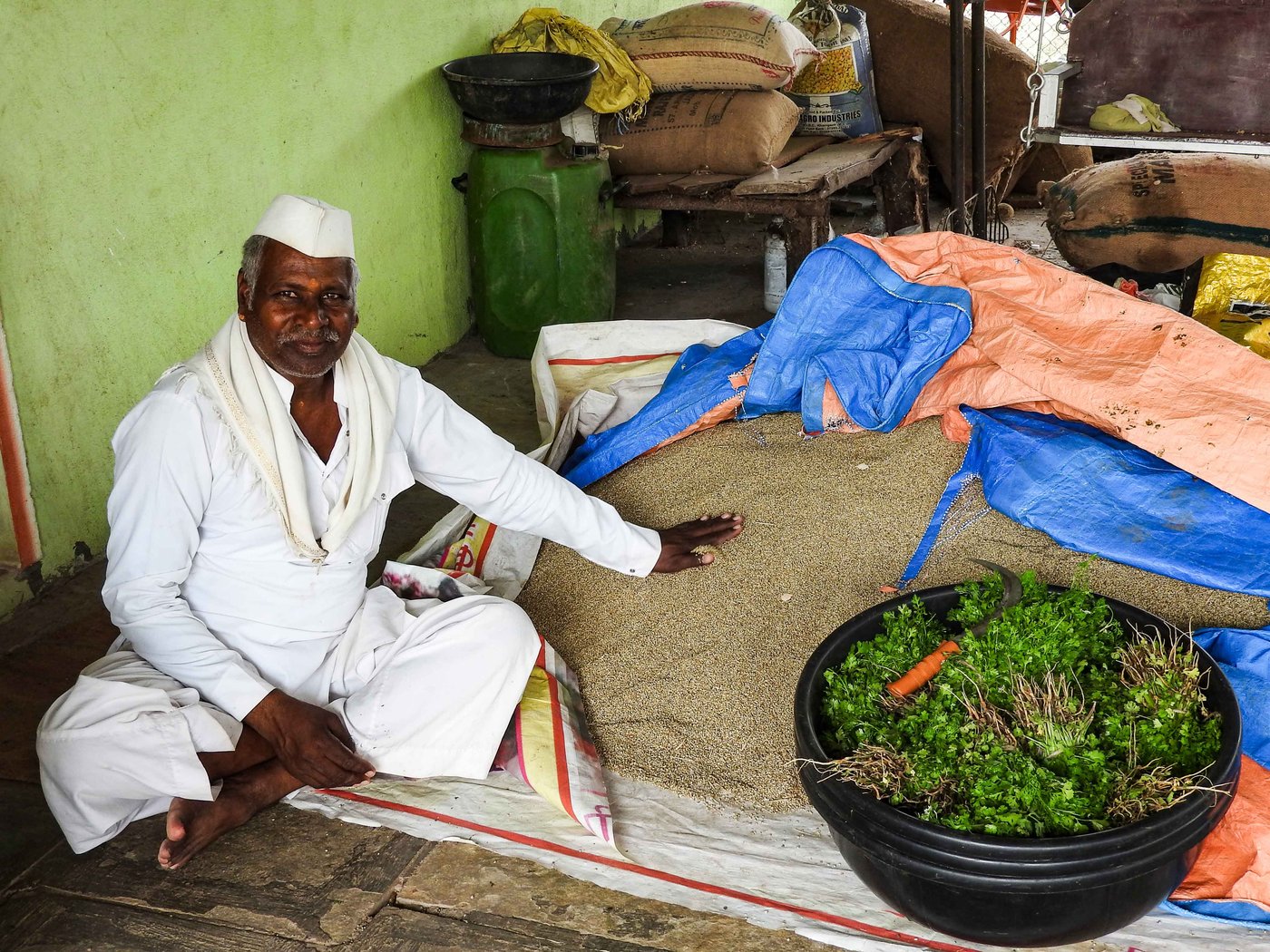 Sonubai's husband sitting beside the farm produced maize and vegetables